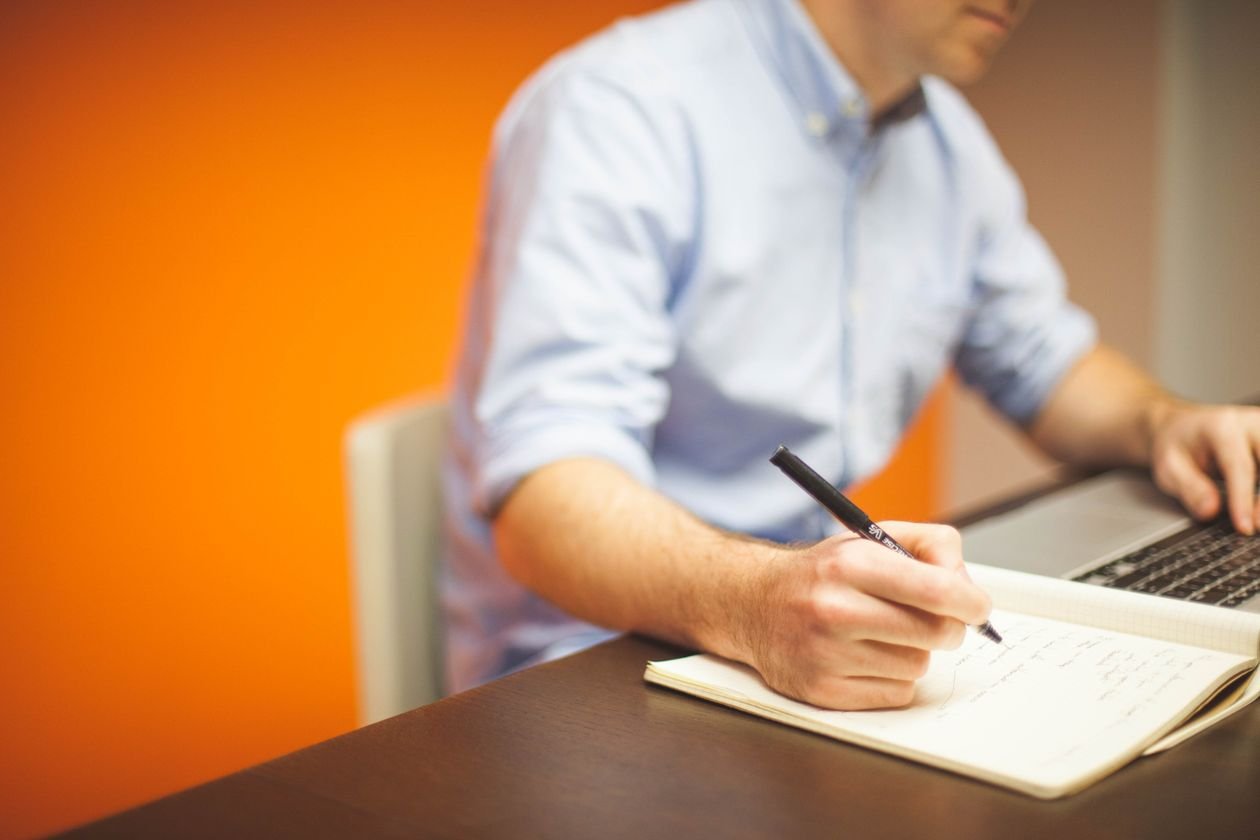 Faculty member writing a course policy at a laptop, representing the process of drafting an AI use policy for a syllabus