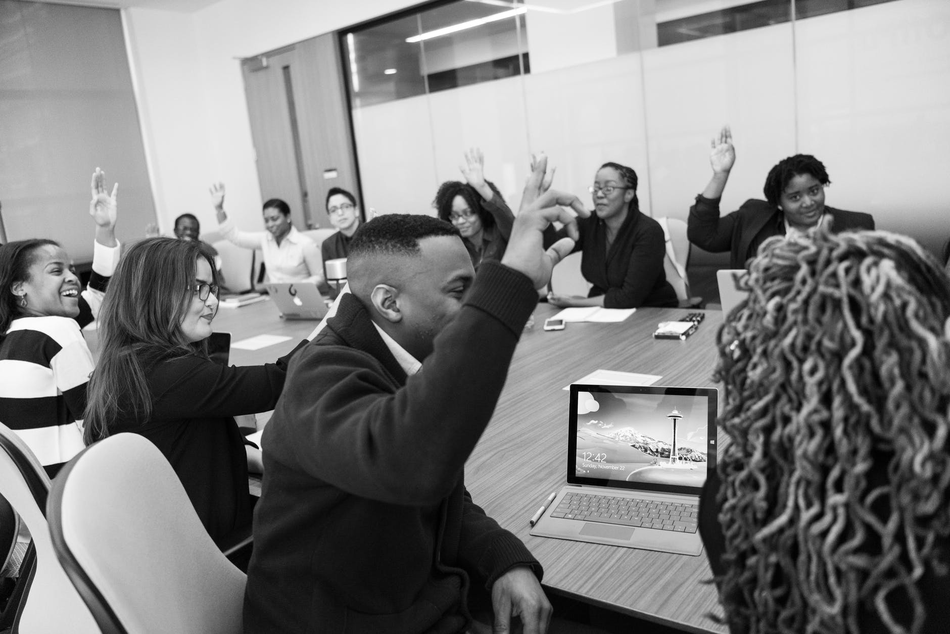 grayscale photo of group of people raises hands